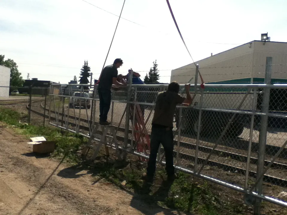 IMG_0143 Two people working on a wire fence outdoors.