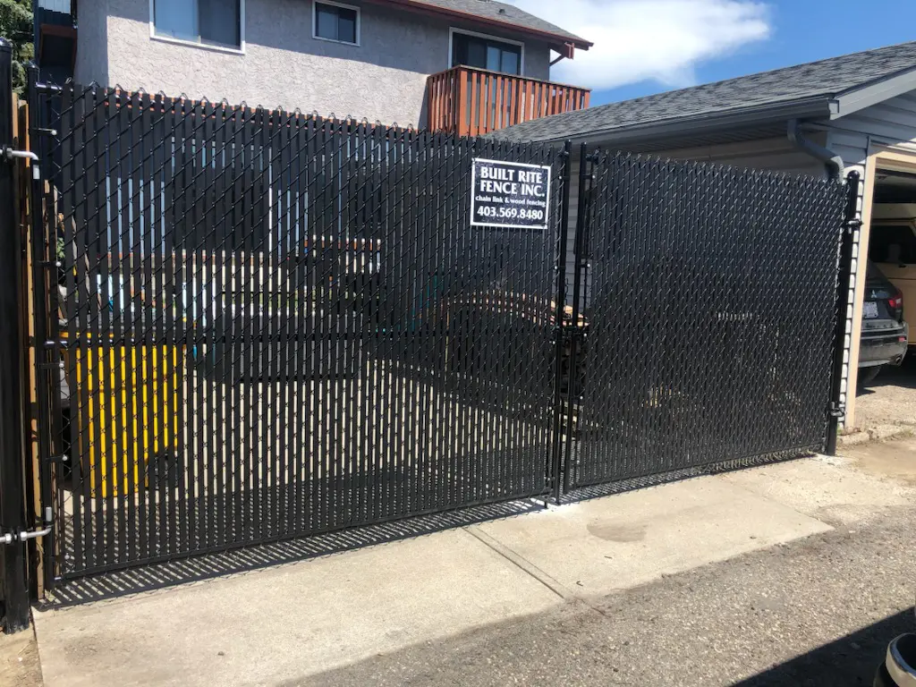 IMG_49341 A black metal gate with a sign and a concrete pathway.