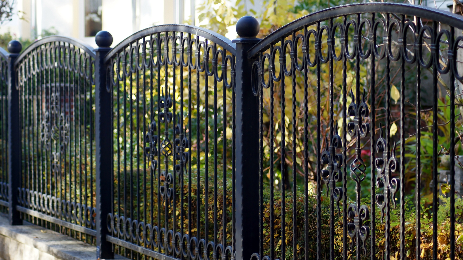 Decorative iron fence with autumn foliage background.