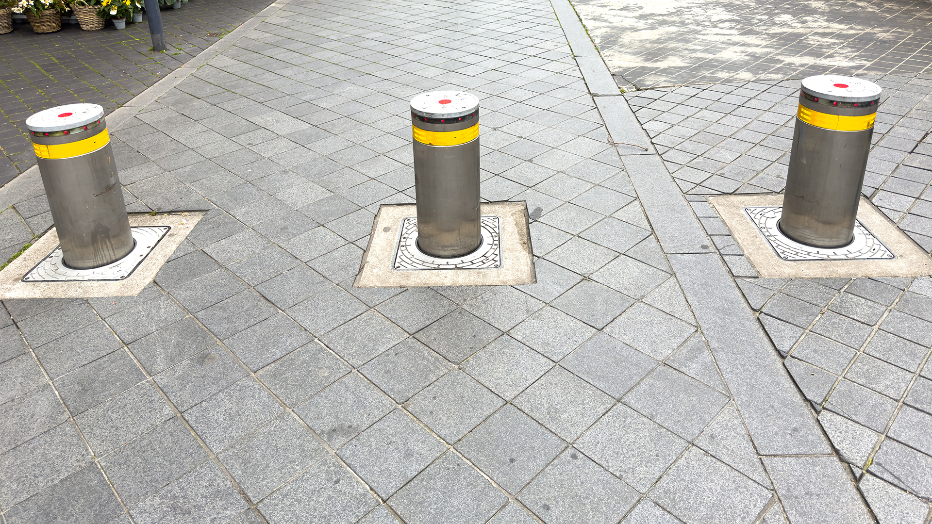 Three metal bollards on paved sidewalk.