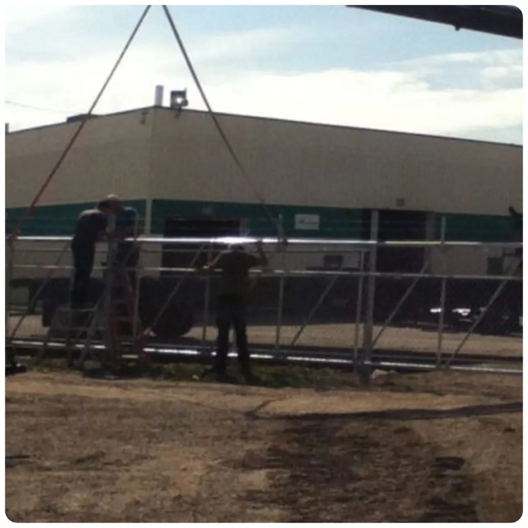 Two workers installing a chain-link fence.