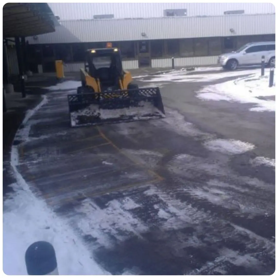 Snowplow clearing snowy parking lot.