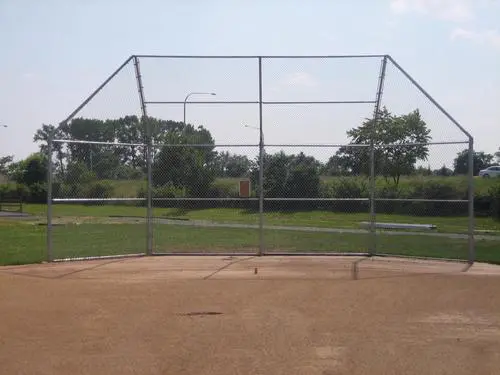 Empty baseball backstop in a grassy field.