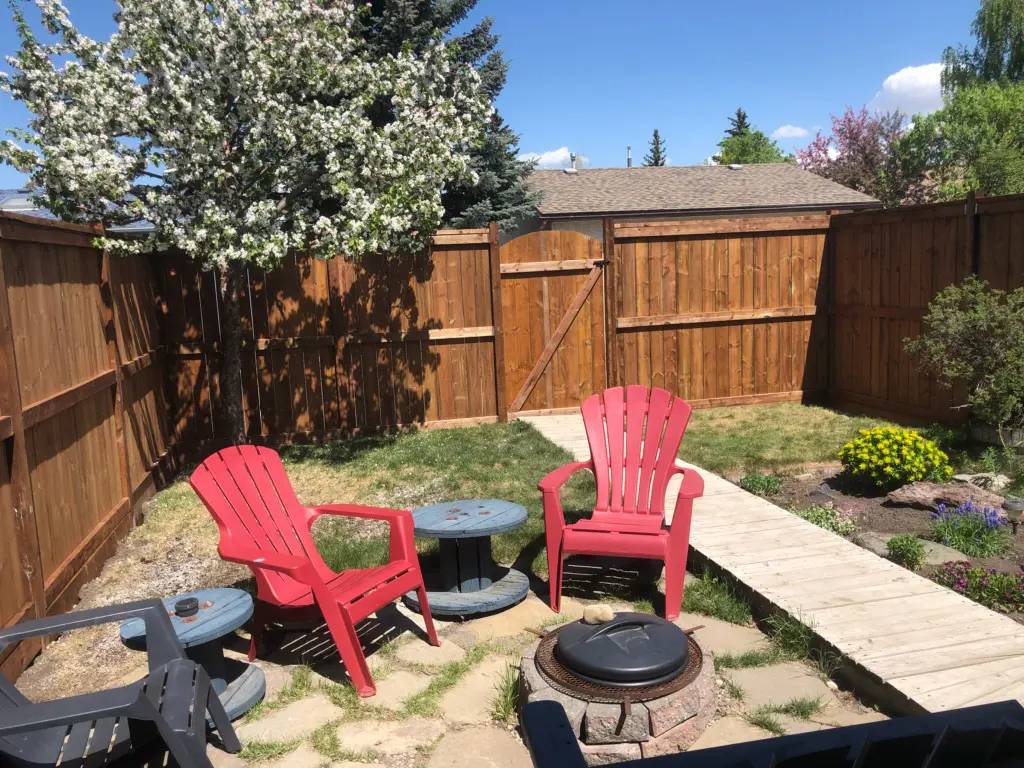 Backyard with chairs, fire pit, and trees.
