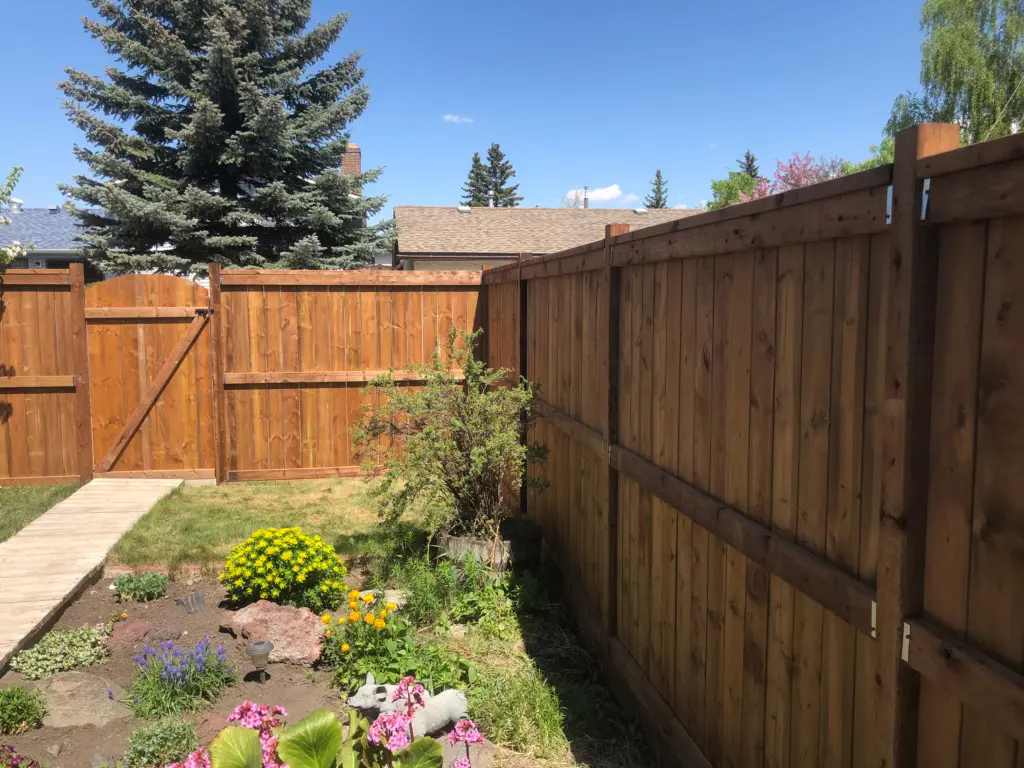 Wooden fence surrounding a garden with flowers.