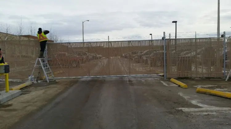 Worker installing security camera on fence.