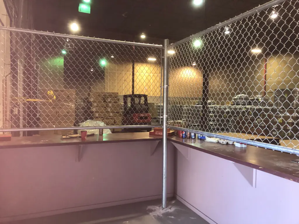 insidep3 An empty cage with metal fencing and a pink base indoors.