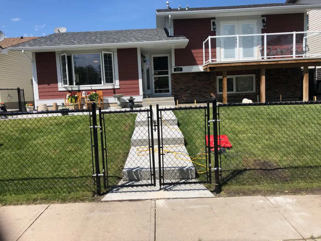 IMG_19951 A small fenced front yard with a sidewalk leading to a house entrance.