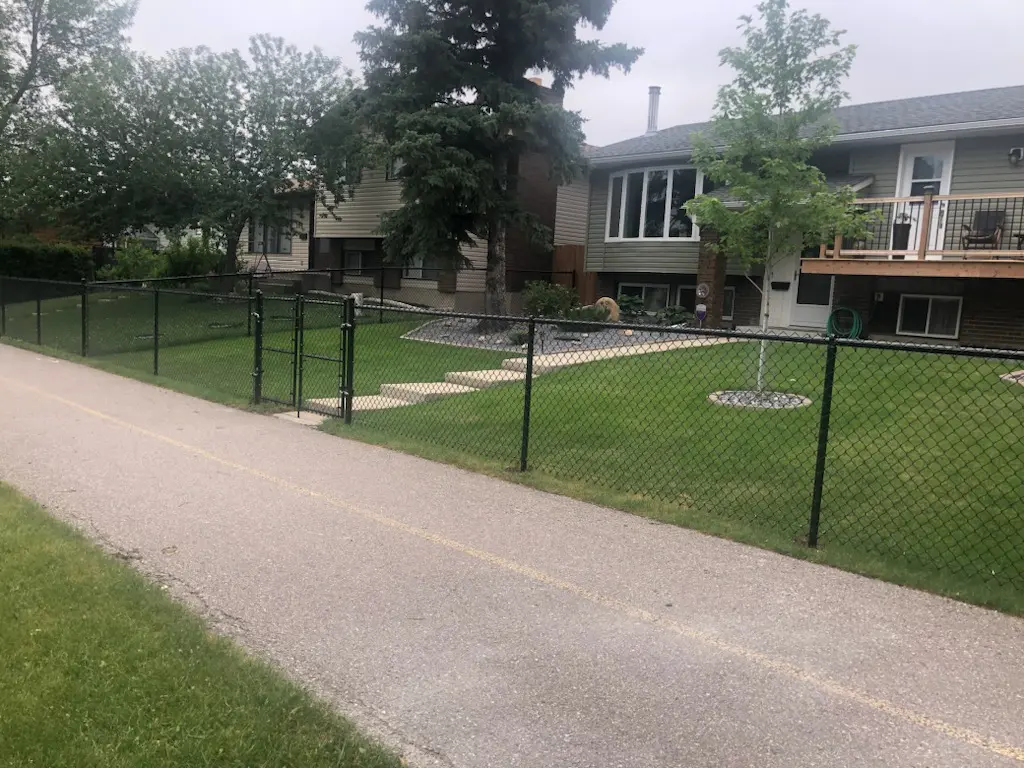 IMG_34771 A suburban house with a green lawn and a black metal fence.