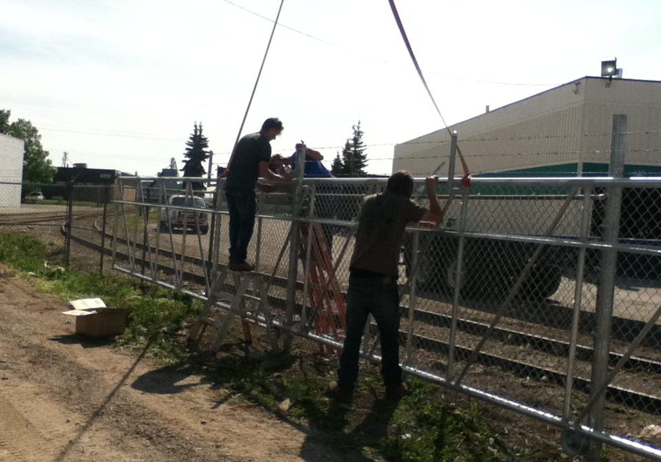 Two people working on a wire fence outdoors.