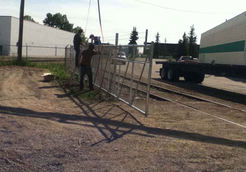 Workers setting up metal scaffolding outdoors in a sunny area.