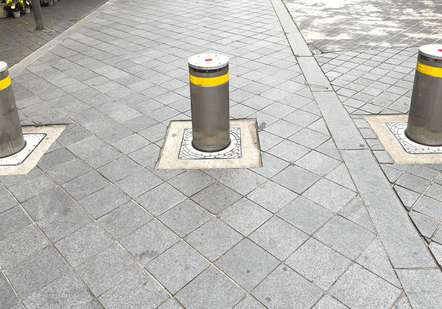 Three metal bollards on paved sidewalk.