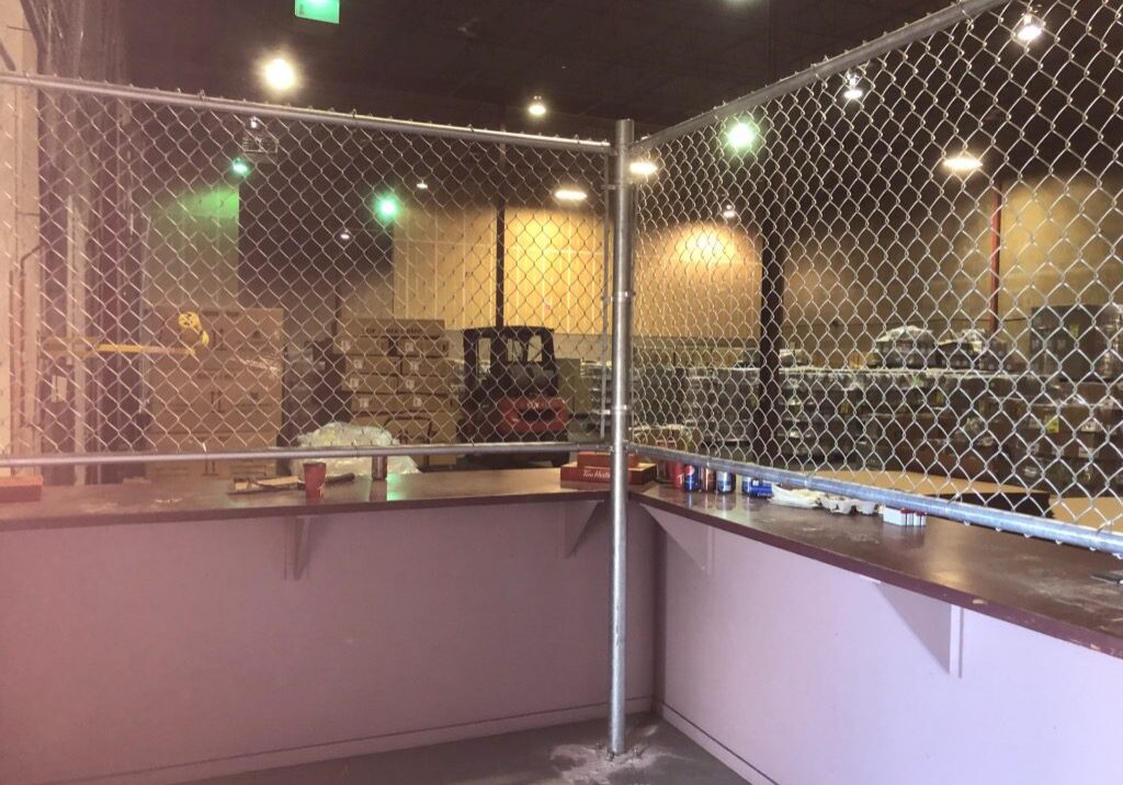 An empty cage with metal fencing and a pink base indoors.